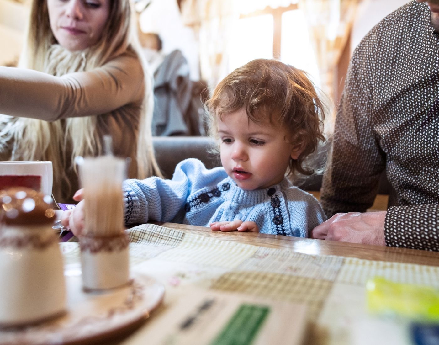 A family with a toddler sitting at a table in a restaurant with a menu in front of them