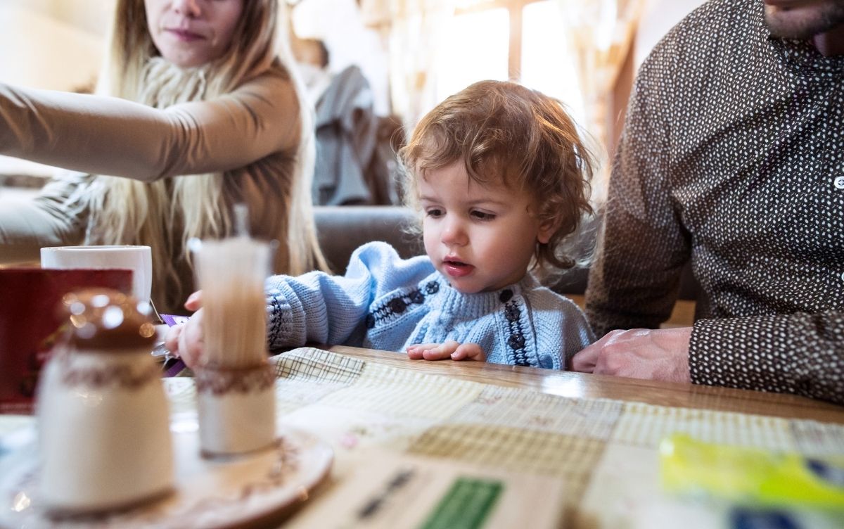 A family with a toddler sitting at a table in a restaurant with a menu in front of them