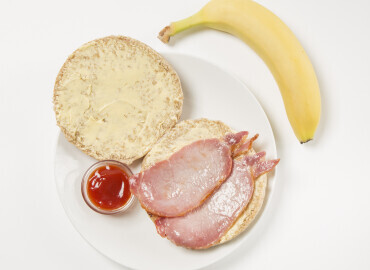 image showing a bacon roll with tomato ketchup and a banana