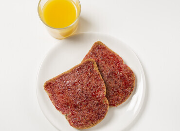 image of a glass of fresh orange juice and 2 thick slices of wholemeal toast with jam