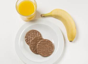 picture of glass of orange juice, chocolate biscuits and a banana