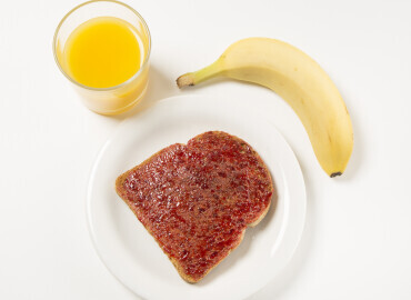 Picture of fresh orange, slice of toast with jam and a banana