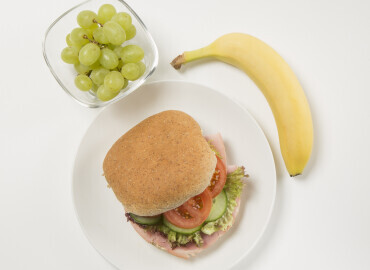 image showing ham salad sandwich, grapes and a banana