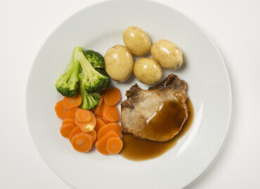 An image showing roast pork chops with potatoes, vegetables and gravy
