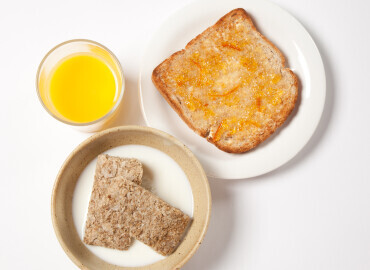 Photo of wheat bisks with a slice of toast with marmalade and a glass of orange juice