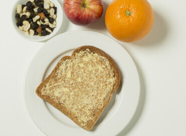 Photo of an apple, orange, raisins and slice of toast with lower fat spread