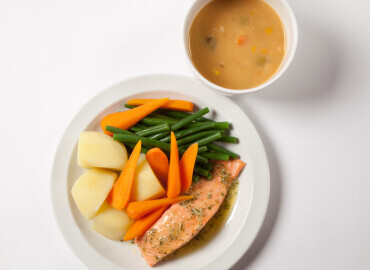 Photo of a bowl of tinned lentil soup and a plate of salmon with potatoes and vegetables