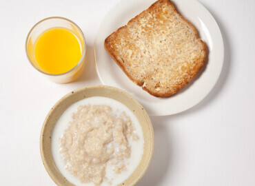Photo of Bowl of porridge, slice of wholemeal toast and lower fat spread, and a glass of fresh orange juice
