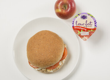Photo of an egg and tomato mayonnaise on a wholemeal roll with a low fat fruit yogurt and an apple