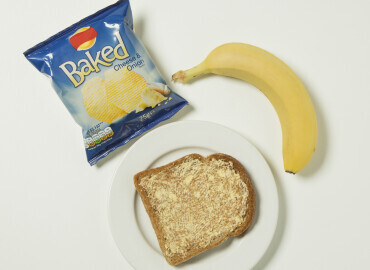Photo of a packet of crisps, banana, and slice of toast with lower fat spread