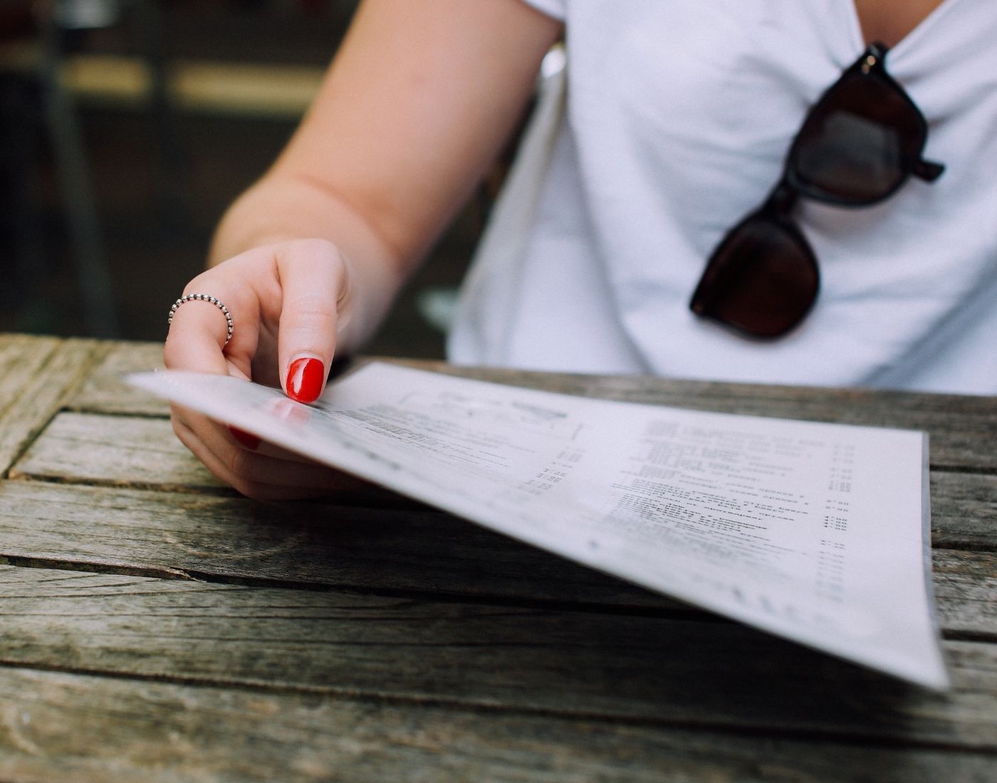 Woman reading a laminated food menu at an outdoor café