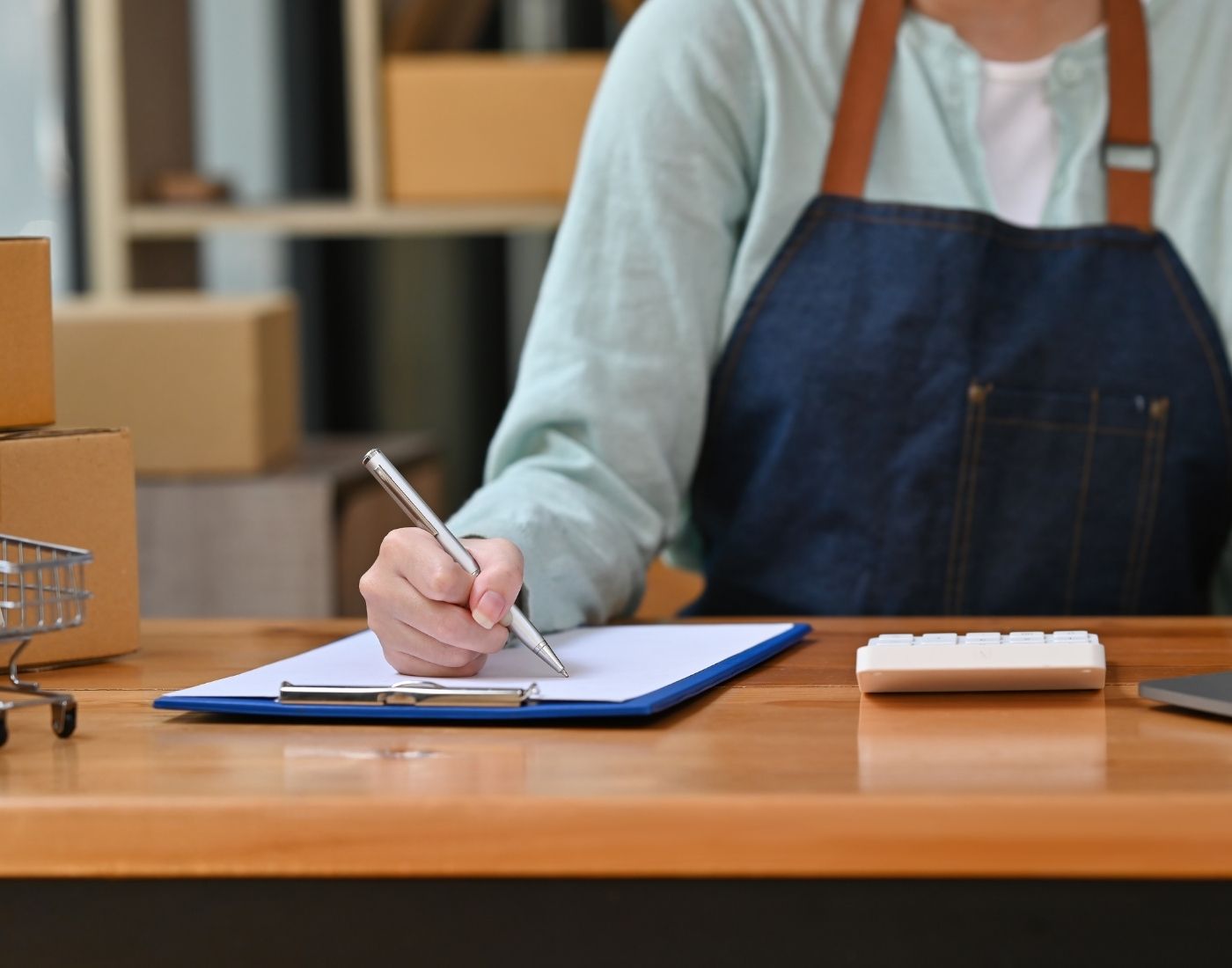 Aproned worker making business calculations in a warehouse