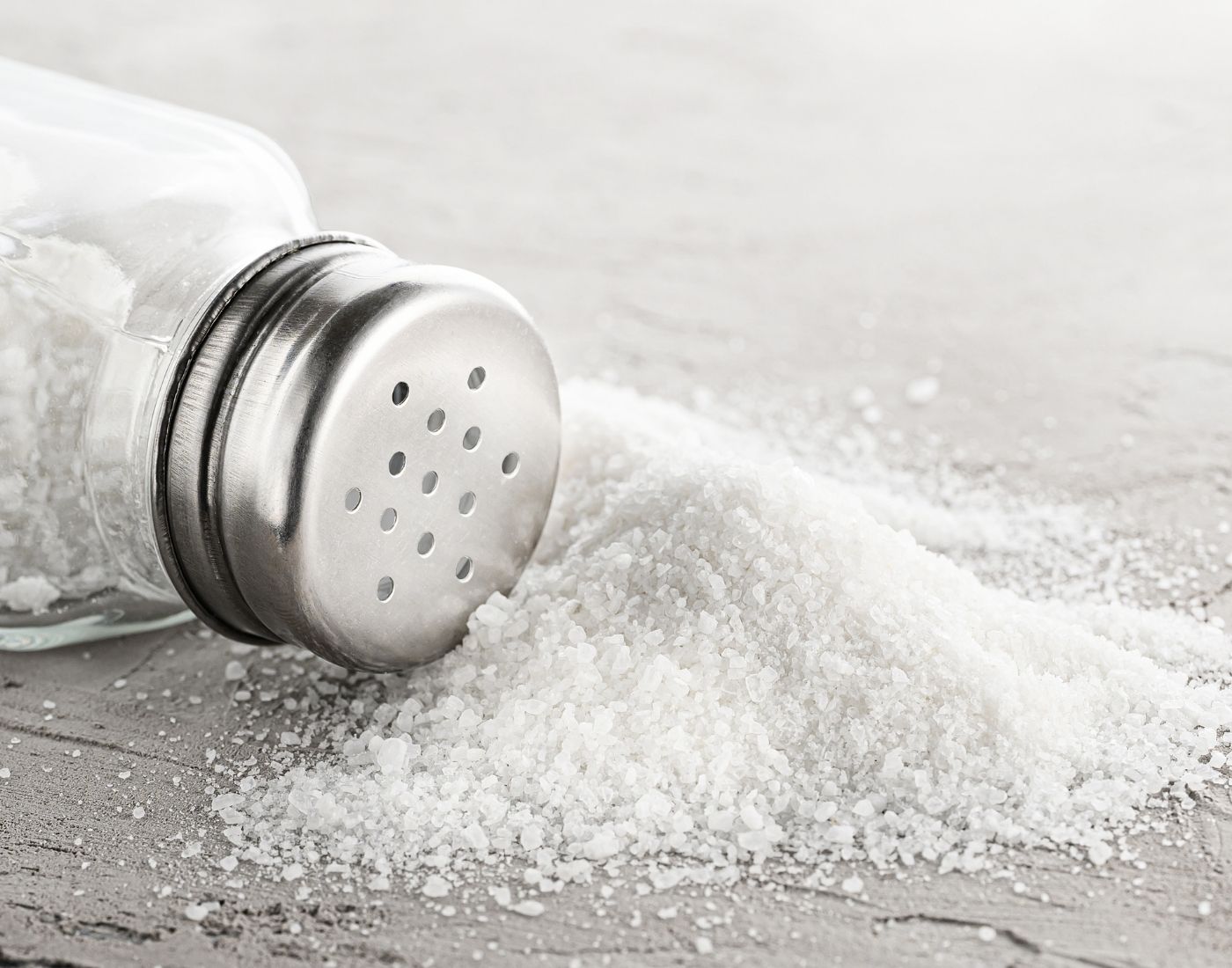 Salt spilled from an overturned salt shaker on a table.