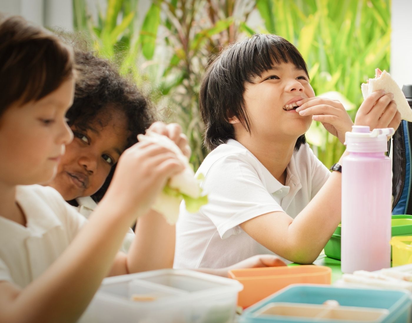 Three children eating their packed lunches.