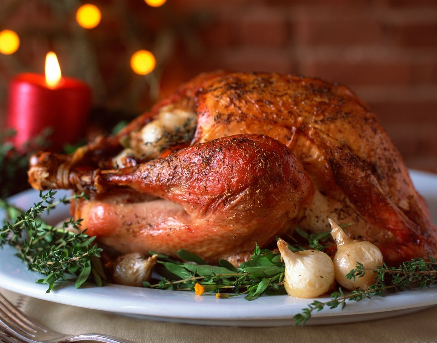 Cooked Christmas turkey on platter next to festive table decorations 
