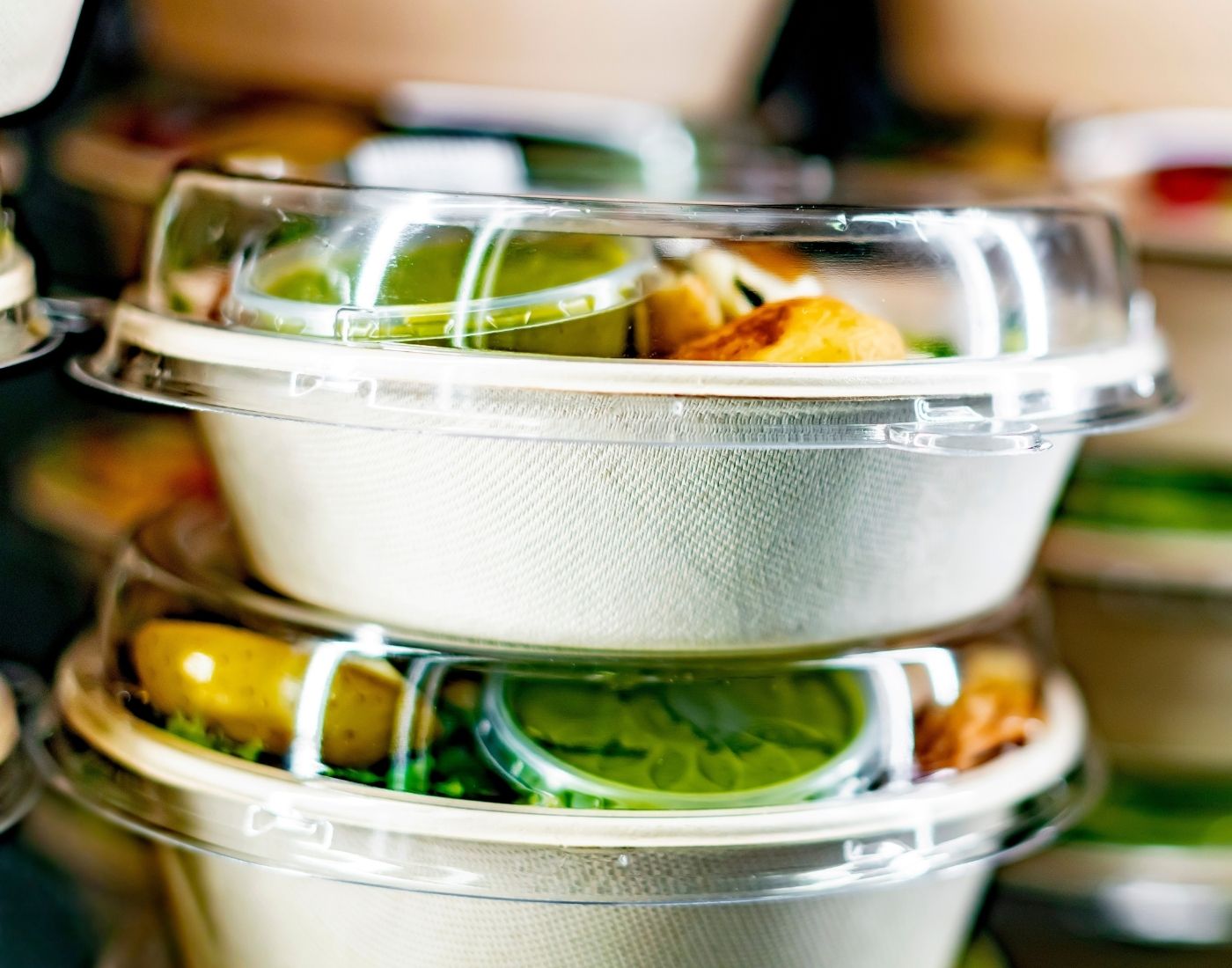 A stack of salads in boxes ready to be sold. The boxes are cardboard with a plastic lid.
