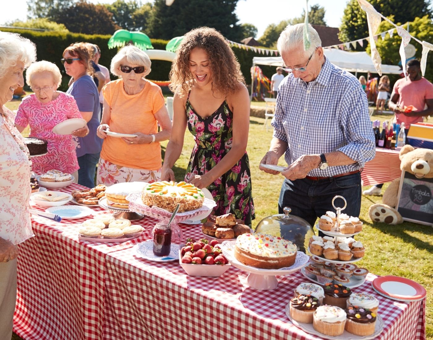 Table of party food with queue of people helping themselves at an outdoor community event