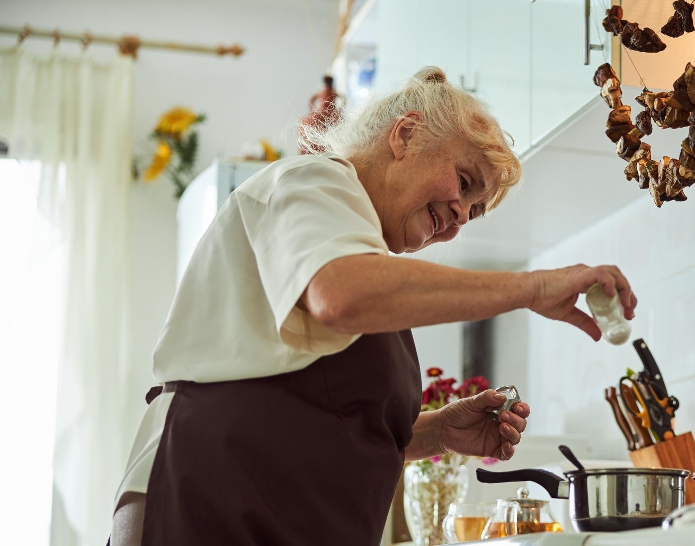 Woman aged over 65 standing at an oven cooking.