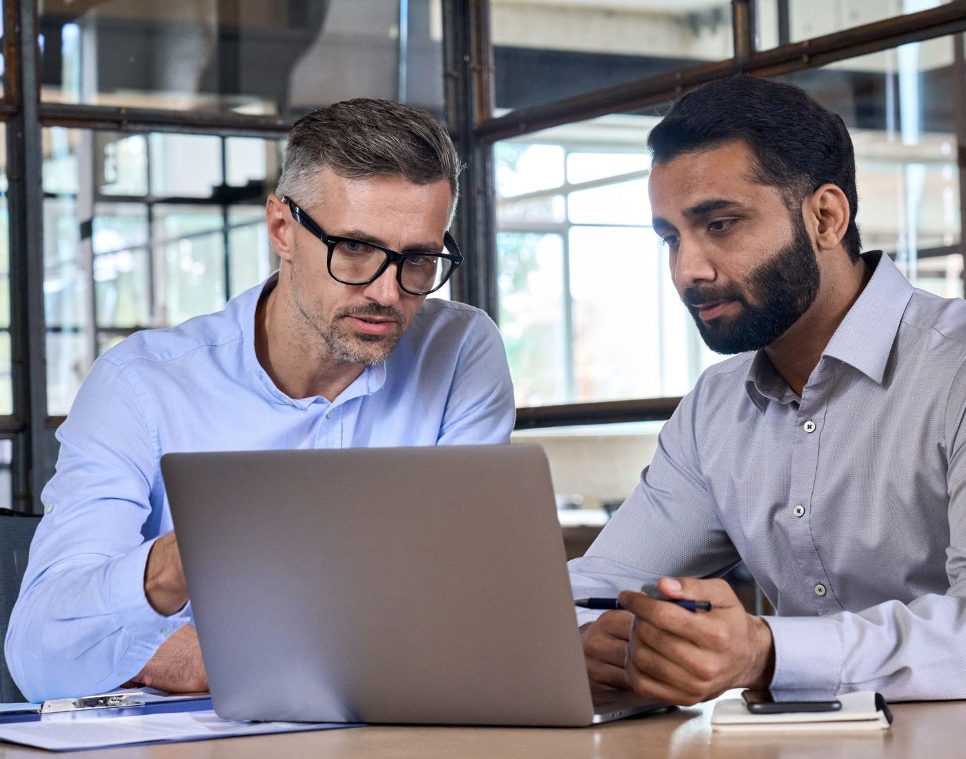 Two male colleagues sitting looking at a computer.