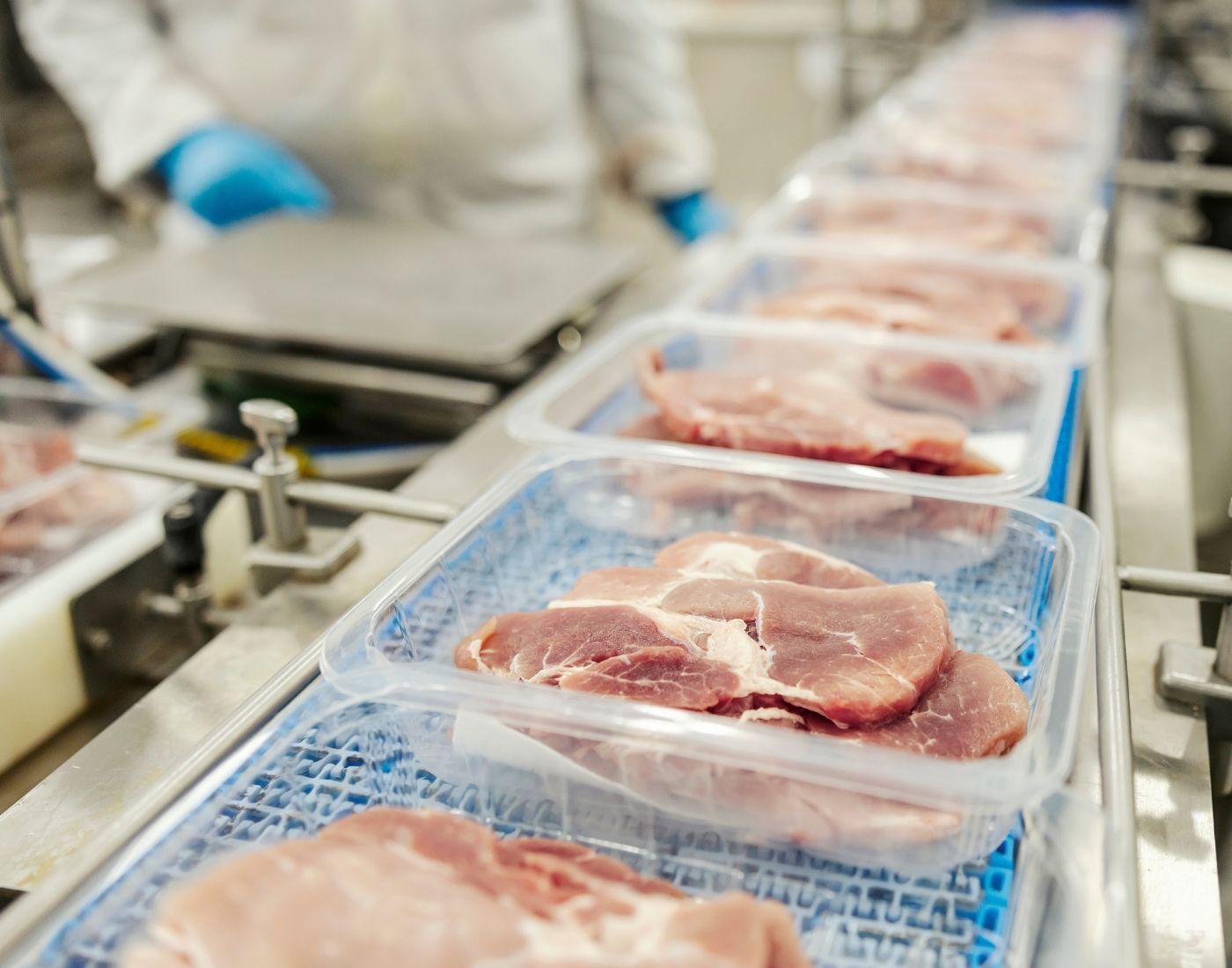 Raw meat being packaged in plastic containers.