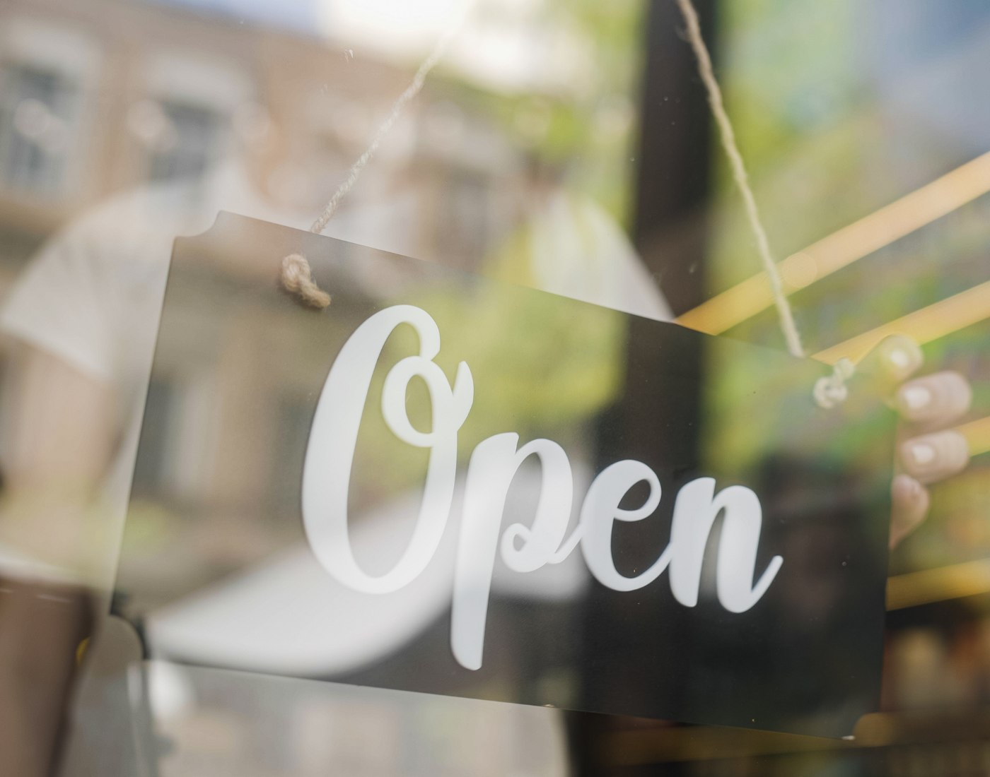 A sign in restaurant or cafe window being flipped to say Open by the hand of a member of staff