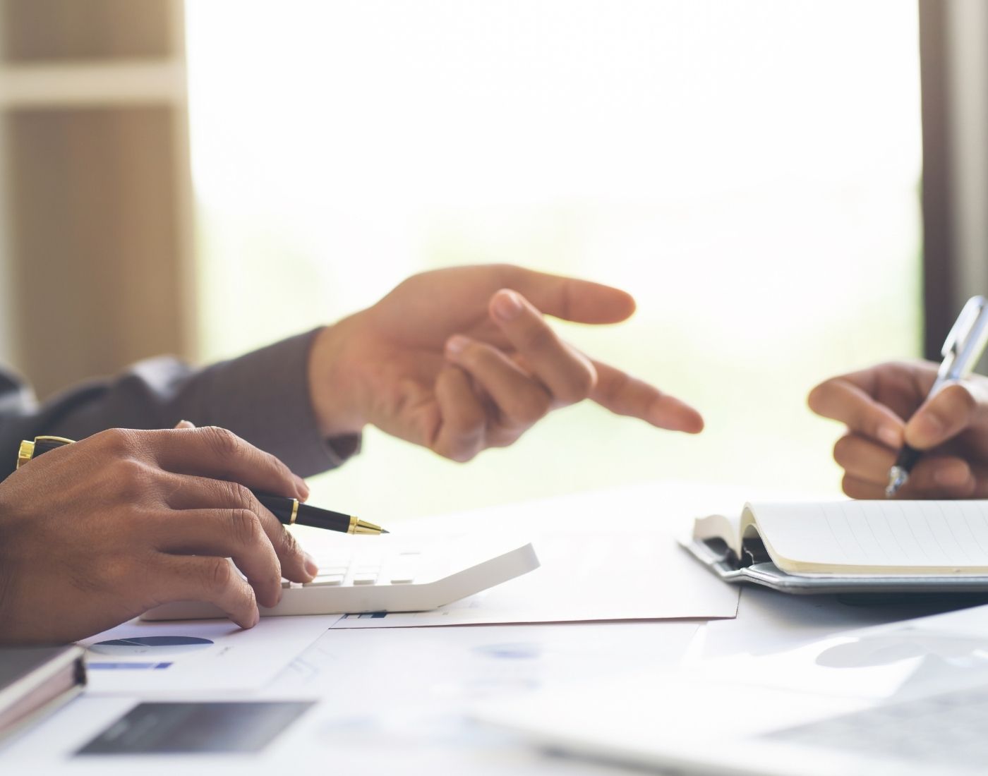 Close up view of two colleagues hands. They're pointing and writing.