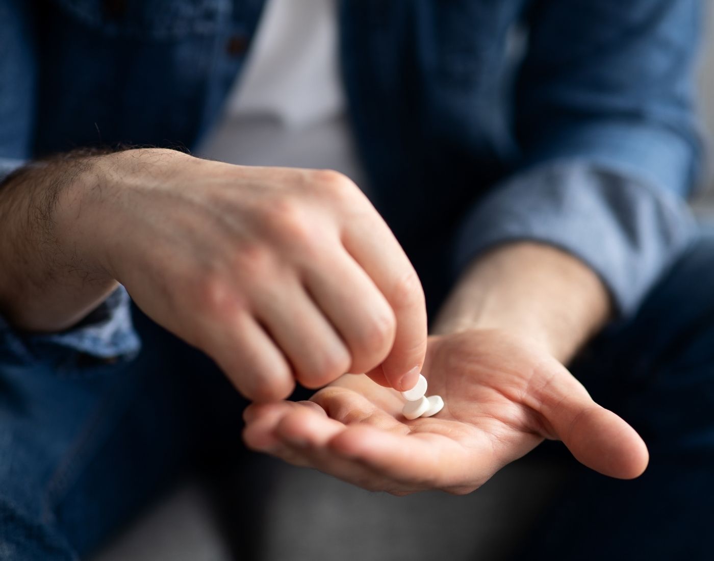 Close-up of a person holding a small white pill in one hand, preparing to take it.