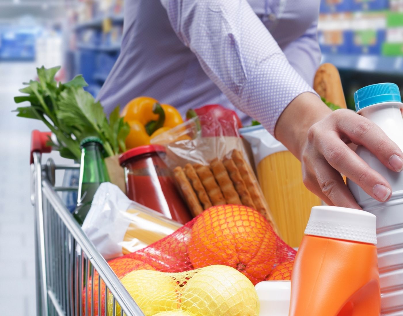 Full shopping trolley. Contains oranges, lemon, crackers, tomato sauce and bread.