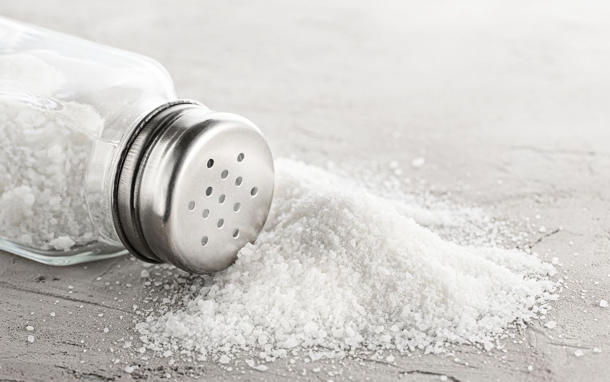 Salt spilled from an overturned salt shaker on a table.
