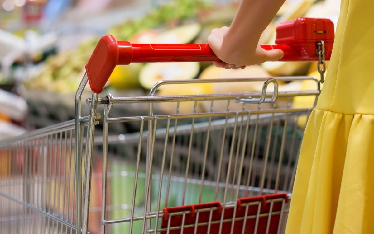 Woman wearing a yellow dress pushing a shopping trolley