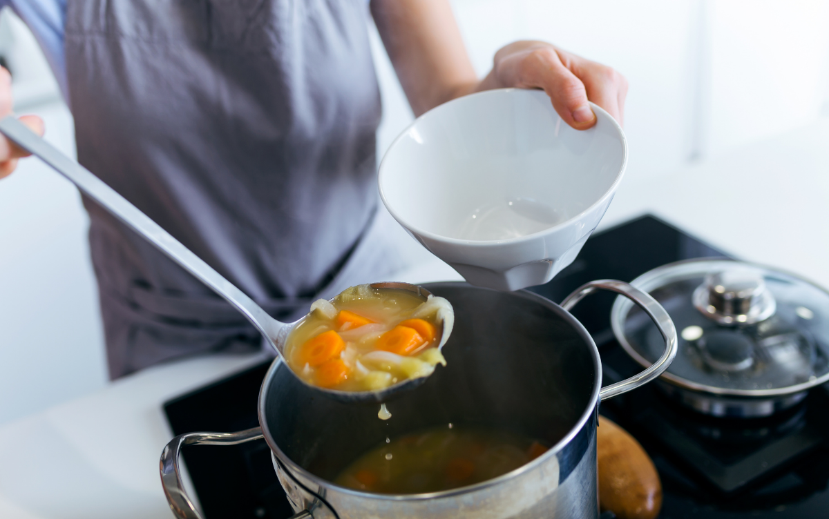 A person serving home made soup from a pan
