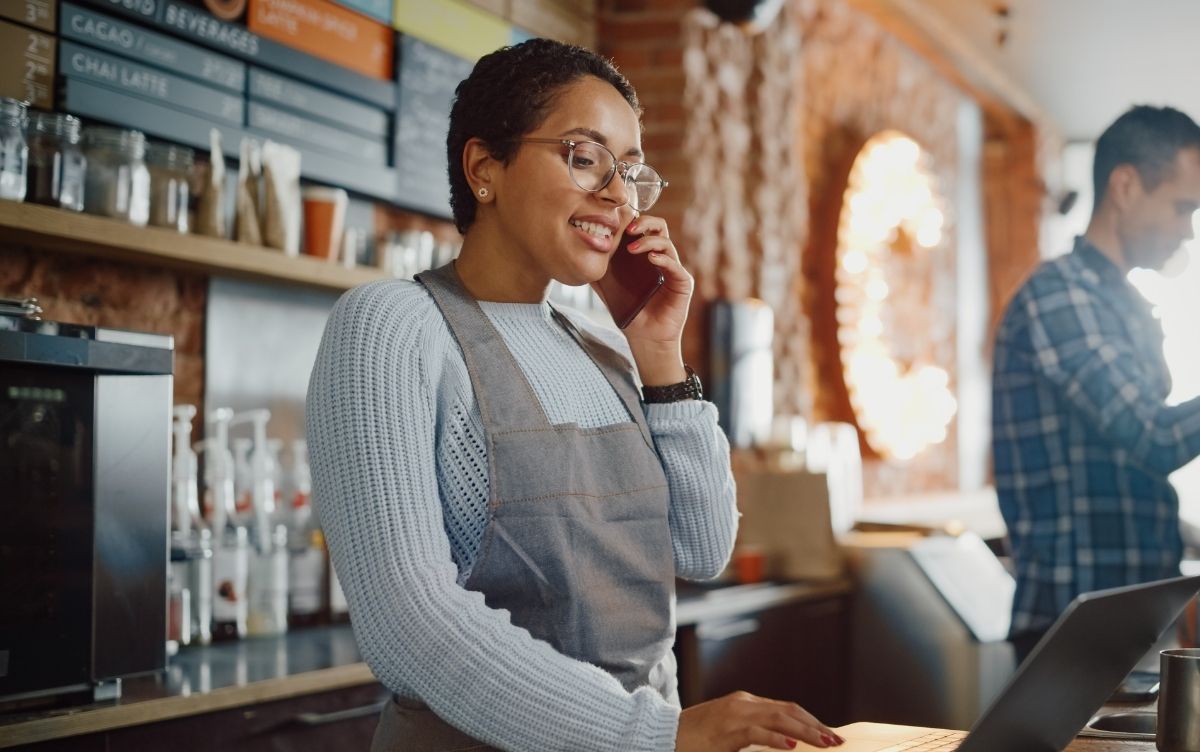 Female cafe owner speaking on the phone and smiling