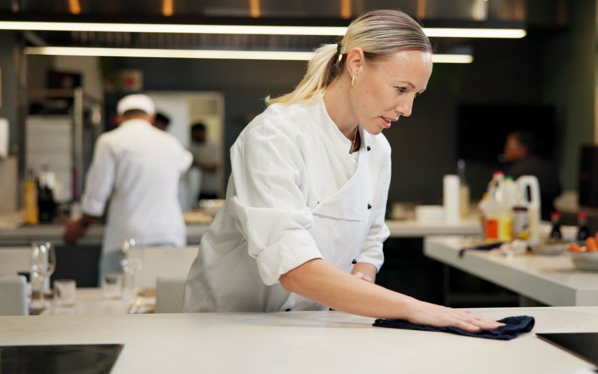 Female chef wiping a restaurant kitchen counter