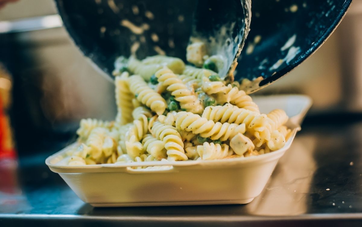 Pasta being poured into a takeaway container.