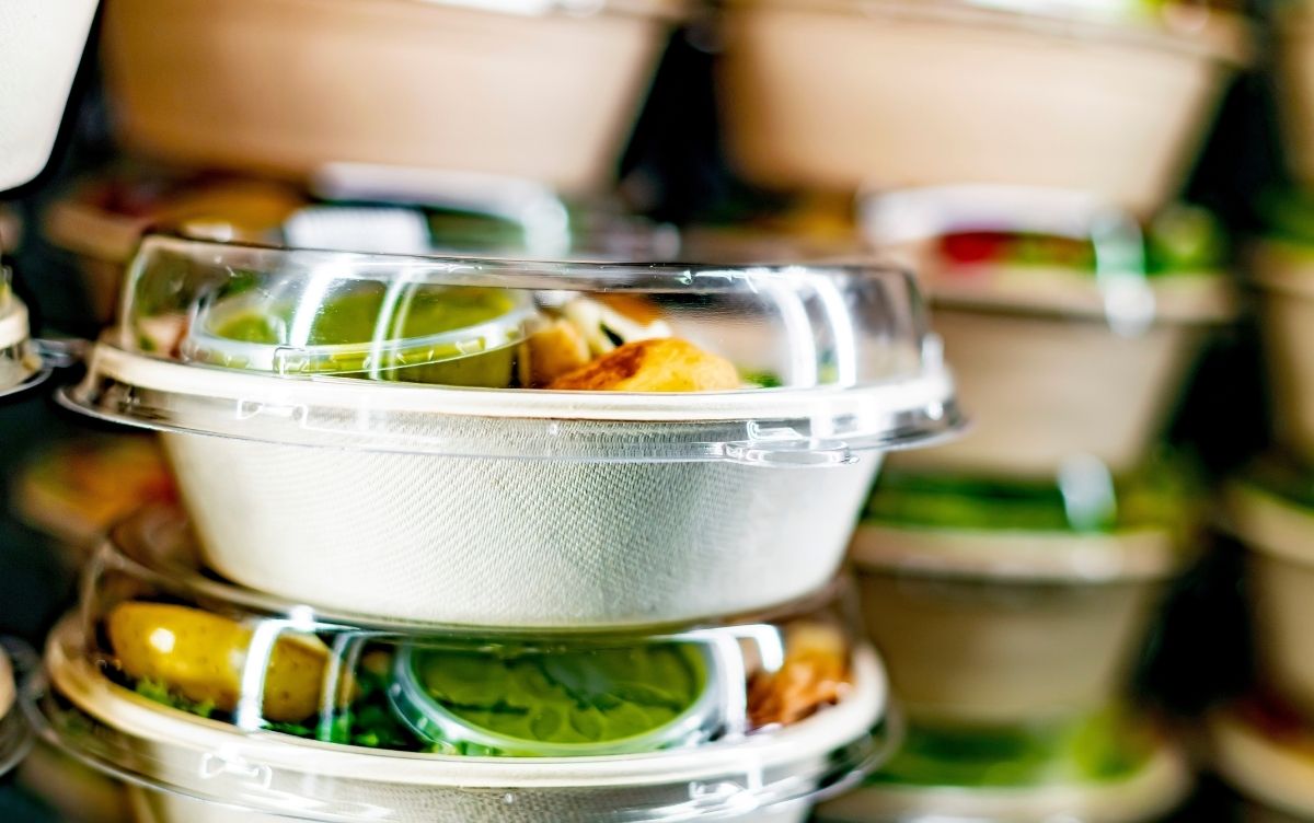 A stack of salads in boxes ready to be sold. The boxes are cardboard with a plastic lid.