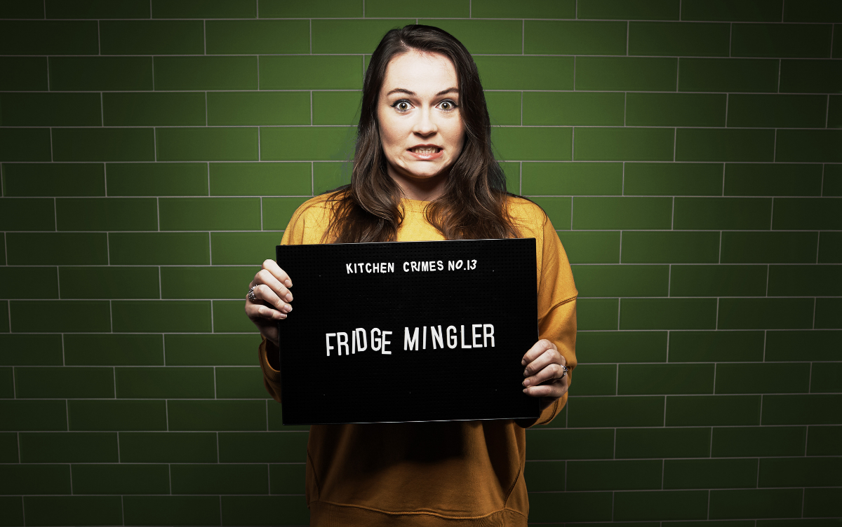 Woman holding mug shot board with words Fridge Mingler