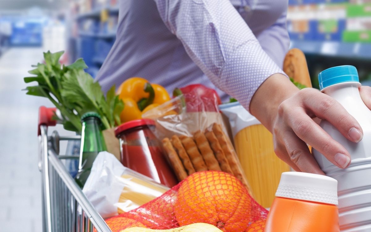 Full shopping trolley. Oranges, bread, crackers, pepper can be seen.