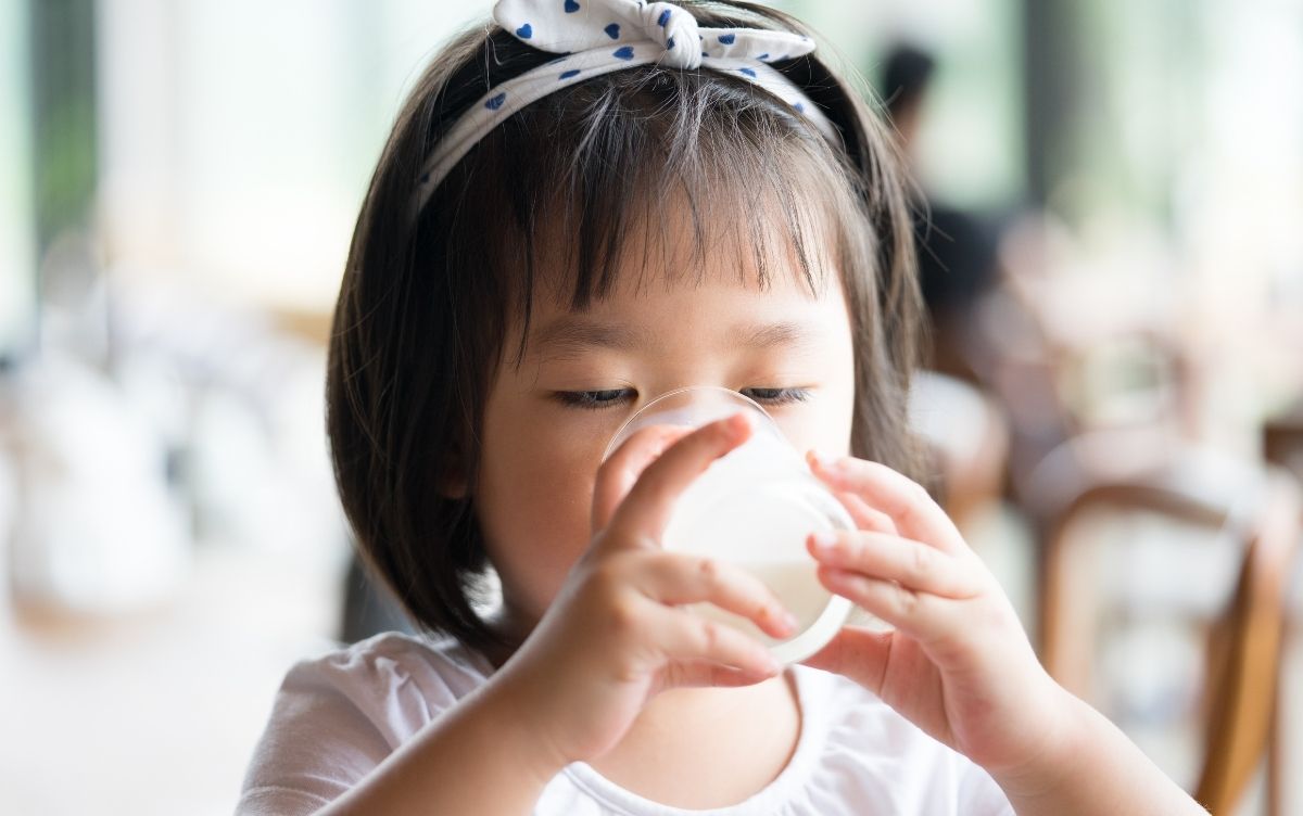 Child drinking from a cup at a café table.
