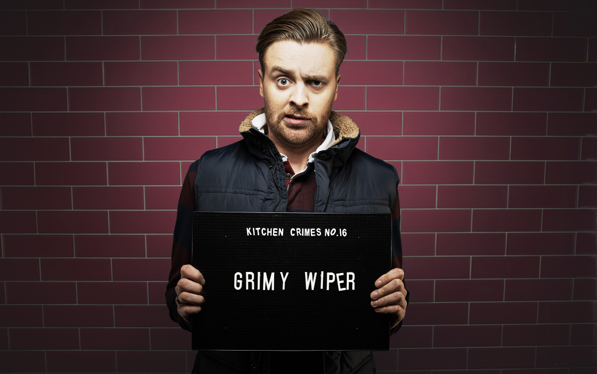 Man holding mug shot board with words Grimy Wiper