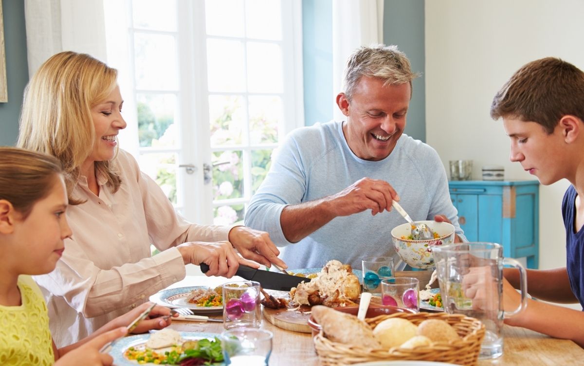 Mum, dad, teenage son and daughter sitting at a table eating a healthy meal.