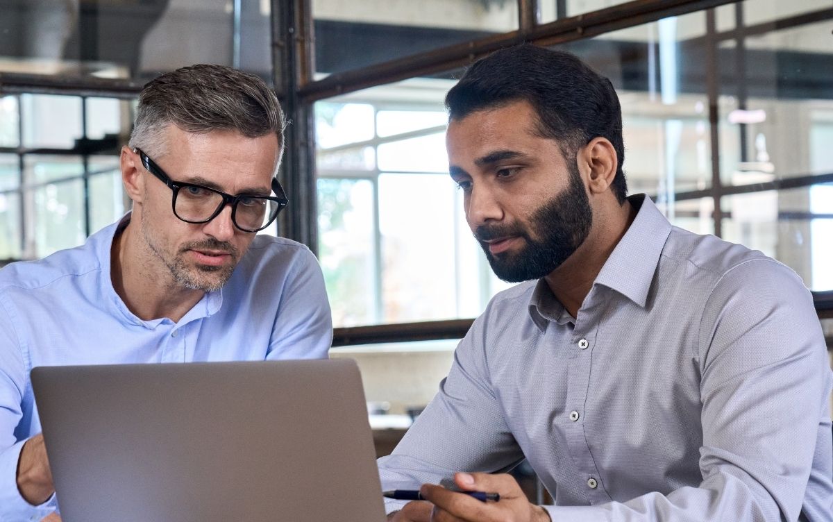 Two male colleagues looking at a laptop computer. 