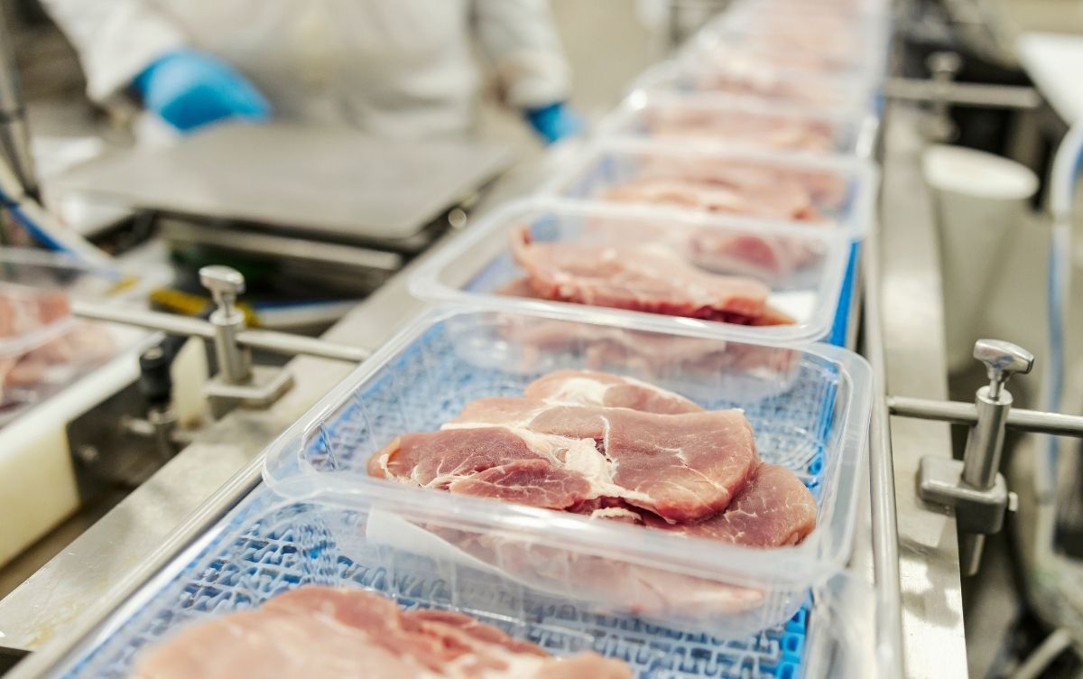 Raw meat being packed in plastic packaging in a factory