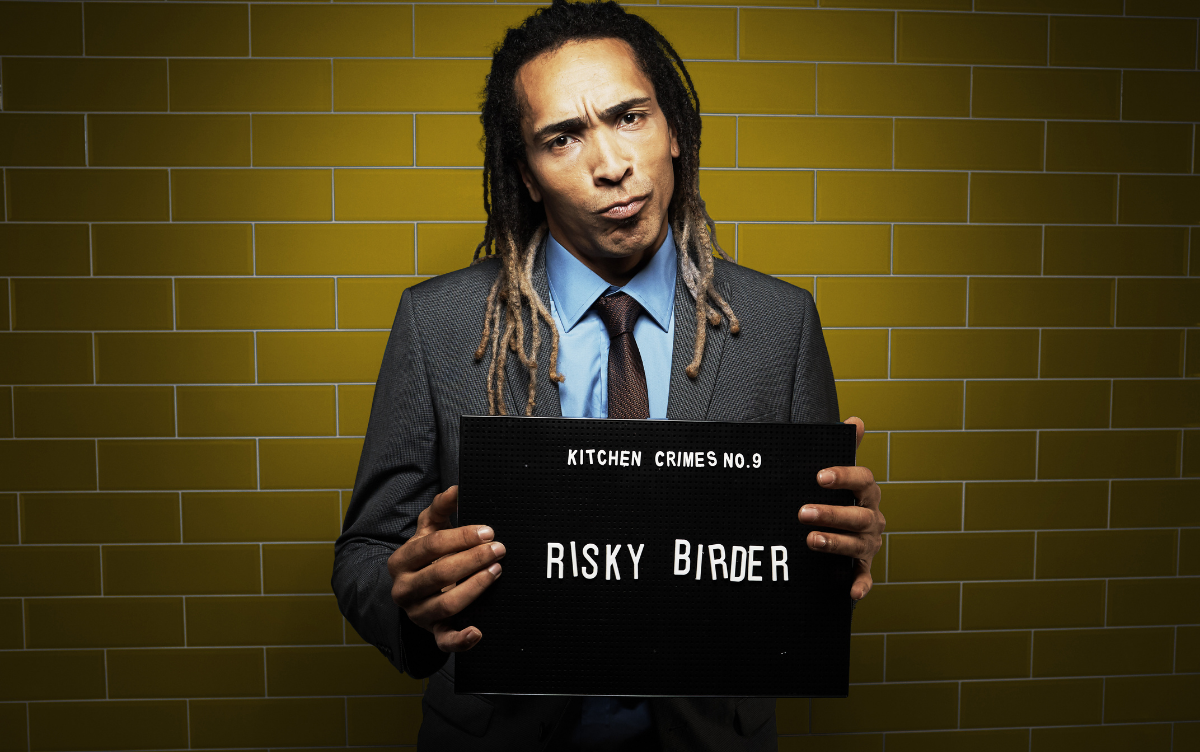 Man holding mug shot board with words Risky Birder