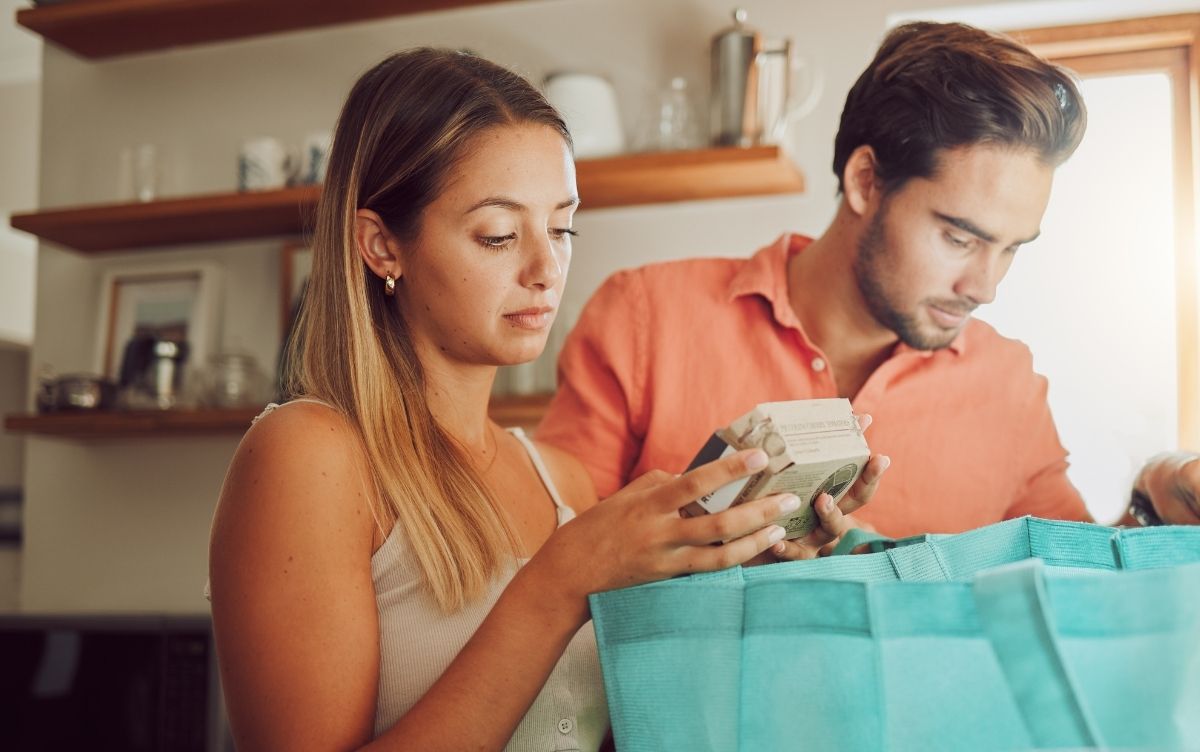 Young woman checking the food label on a small box of food.