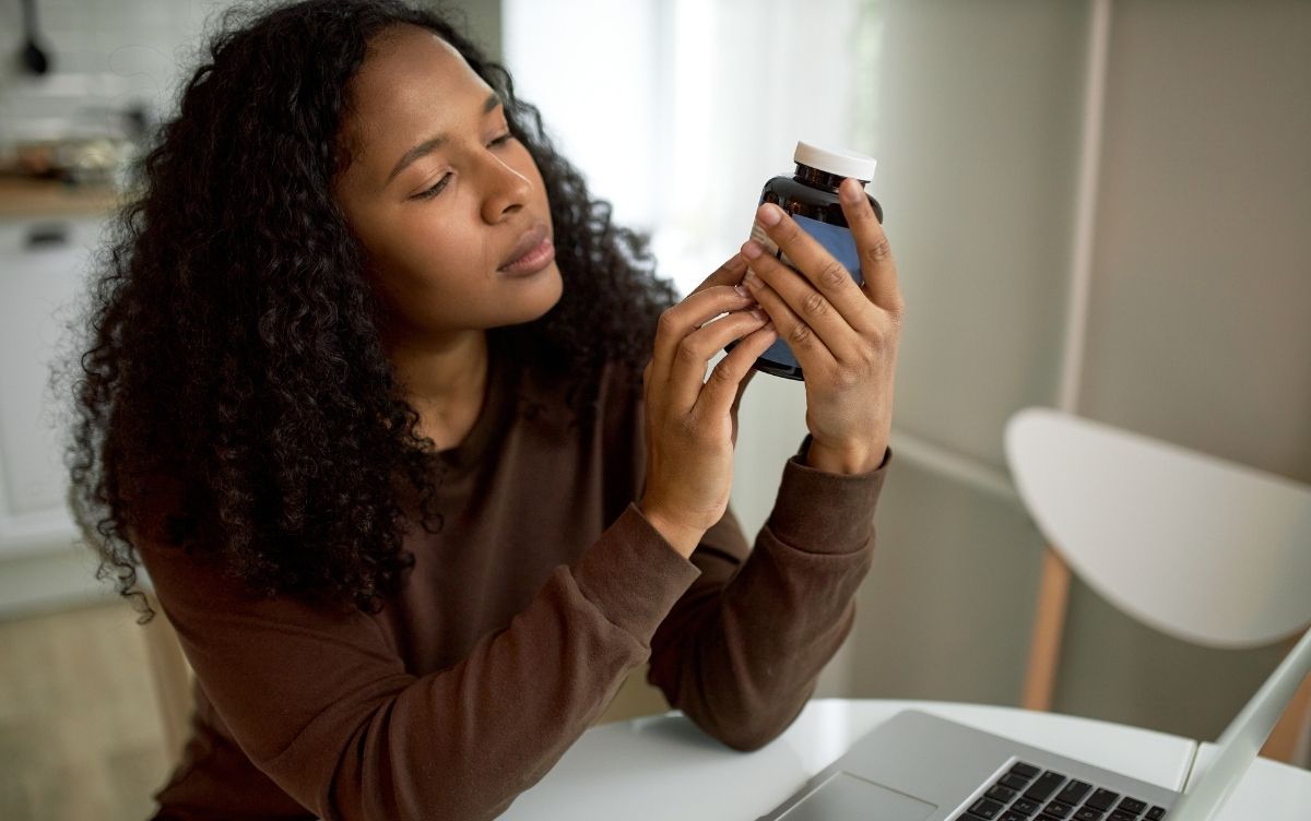 Young woman looking at vitamin bottle