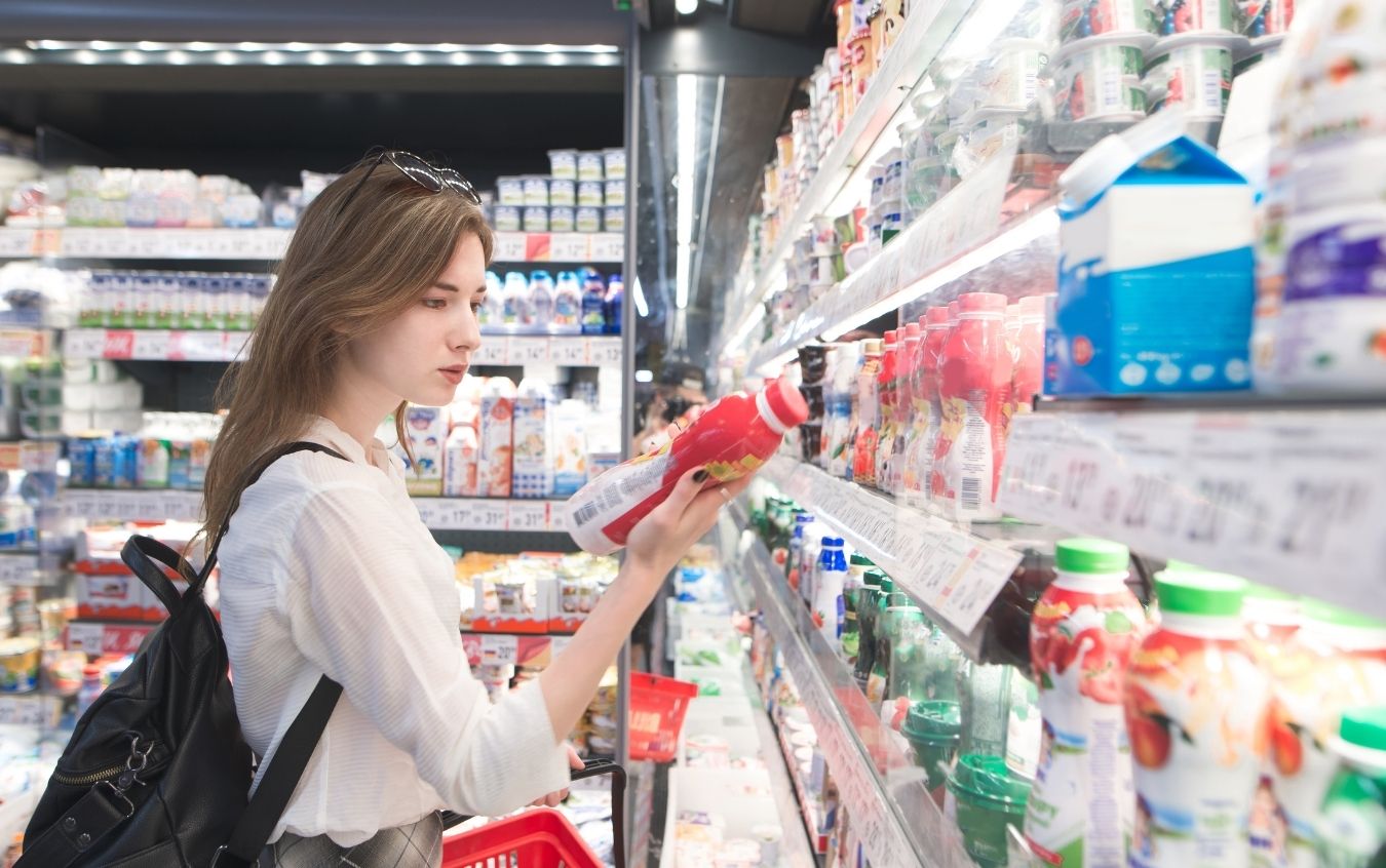 Person typing on a laptop keyboard with both hands, wearing a watch on the left wrist and a ring on the right hand, with a spiral-bound notebook open beside the laptop